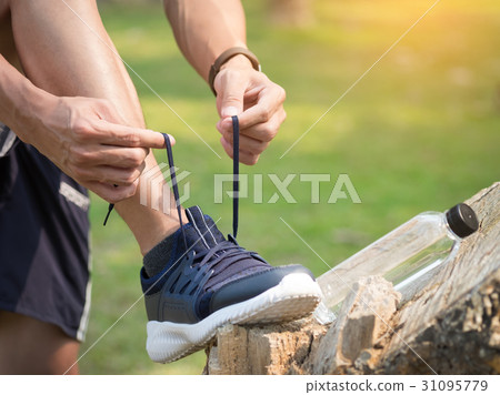 Cropped shot of young man runner tightening running shoe laces, 31095779