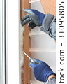 Male hand stuffing insulation in the gap 31095805
