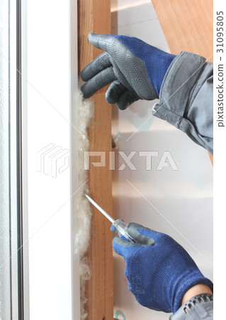 Male hand stuffing insulation in the gap 31095805