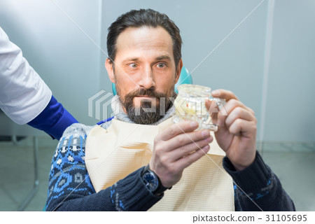 Surprised man holding jaw model. 31105695