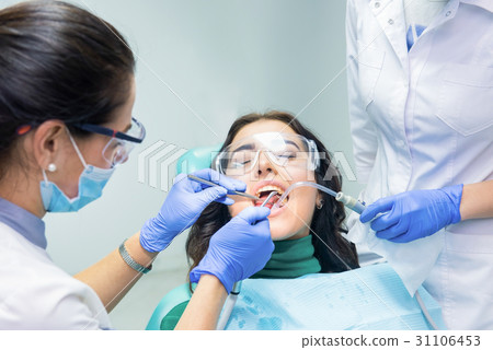 Two dentists working with patient. 31106453