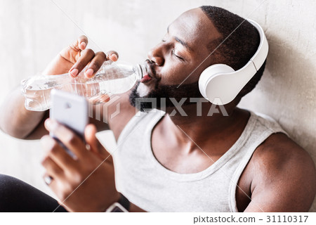 Joyful bearded african sportsman having break of 31110317