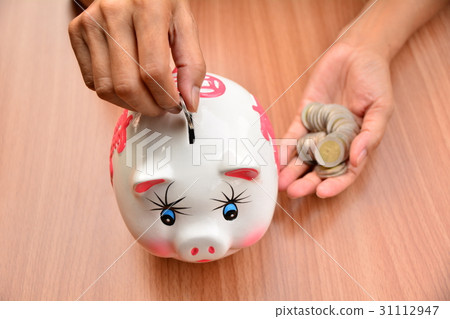 Person putting coin in piggy bank for saving 31112947
