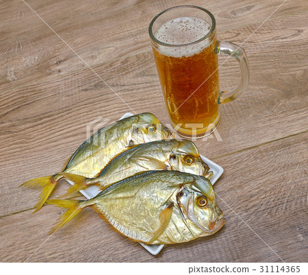 Dried fish and a glass of beer on a wooden table. Dried fish and a glass of beer on a wooden table. 31114365