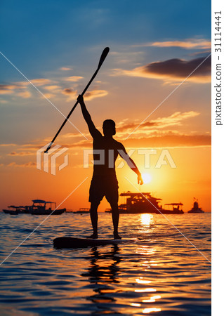 Black silhouette of paddle boarder standing on SUP 31114441