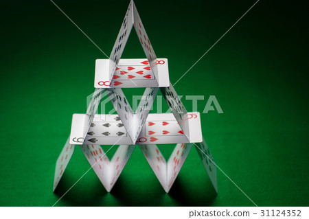 house of playing cards on green table cloth 31124352