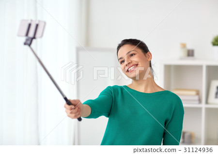 woman taking selfie by smartphone monopod at home 31124936