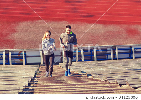 happy couple running upstairs on stadium 31125000
