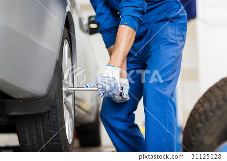 mechanic with screwdriver changing car tire mechanic with screwdriver changing car tire 31125128