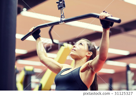 woman flexing arm muscles on cable machine in gym 31125327