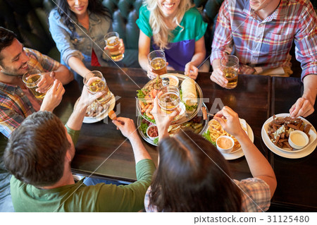 happy friends eating and drinking at bar or pub happy friends eating and drinking at bar or pub 31125480