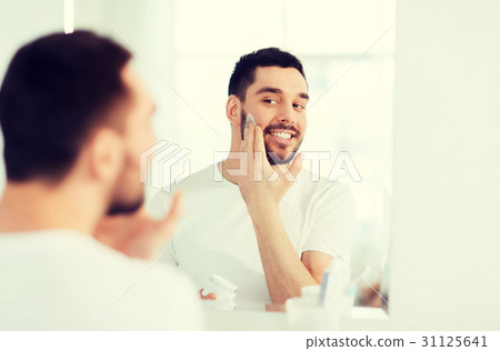 happy young man applying cream to face at bathroom 31125641