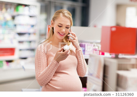 happy pregnant woman with smartphone at pharmacy 31126360