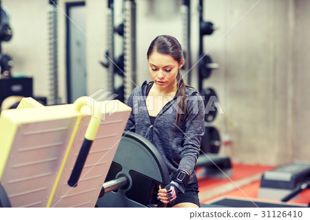 young woman adjusting leg press machine in gym 31126410