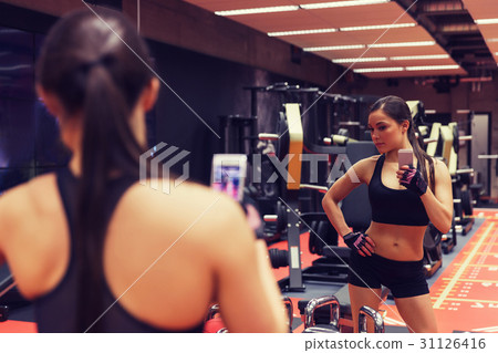 woman with smartphone taking mirror selfie in gym 31126416