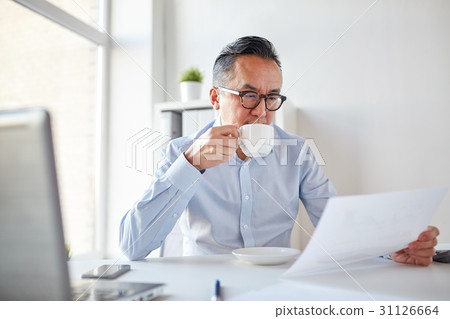 businessman with papers drinking coffee at office businessman with papers drinking coffee at office 31126664