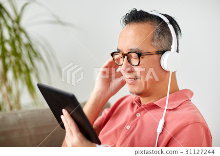 man with tablet pc and headphones at home 31127244