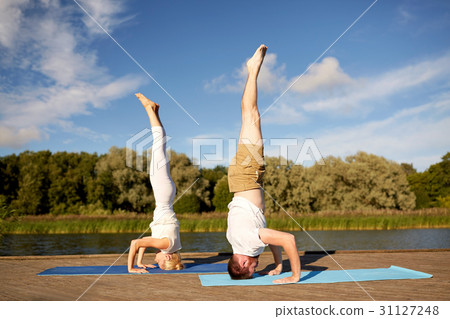 couple making yoga headstand on mat outdoors couple making yoga headstand on mat outdoors 31127248