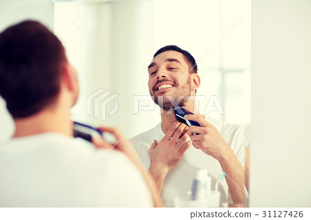 man shaving beard with trimmer at bathroom 31127426