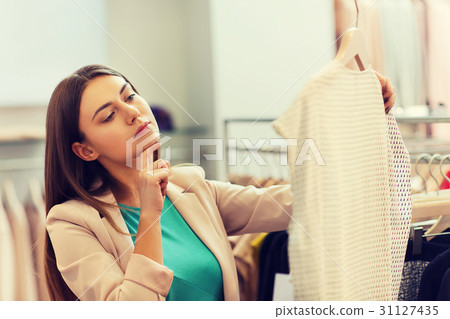 thoughtful young woman choosing clothes in mall thoughtful young woman choosing clothes in mall 31127435