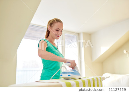 happy woman with iron and ironing board at home 31127559