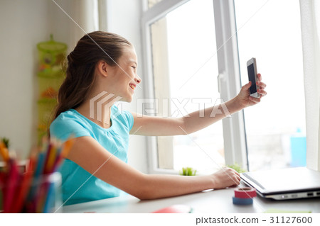 happy girl with smartphone taking selfie at home happy girl with smartphone taking selfie at home 31127600