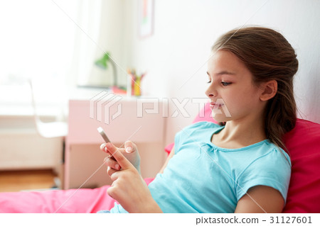 smiling girl texting on smartphone at home smiling girl texting on smartphone at home 31127601
