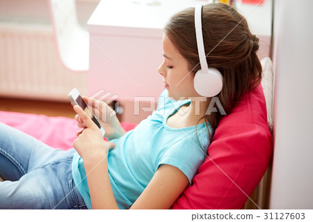 happy girl with smartphone and headphones at home 31127603