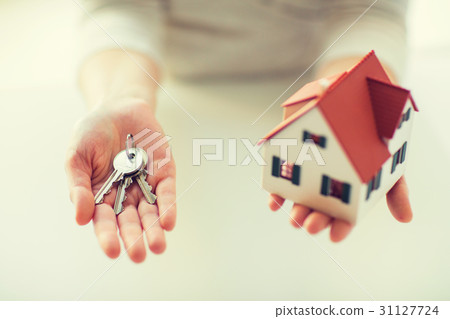 close up of hands holding house model and keys 31127724