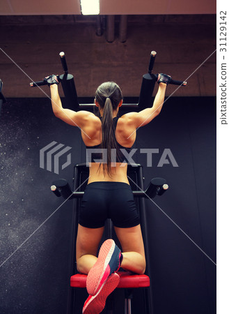 woman exercising and doing pull-ups in gym 31129142