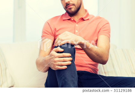 close up of man suffering from pain in leg at home close up of man suffering from pain in leg at home 31129186