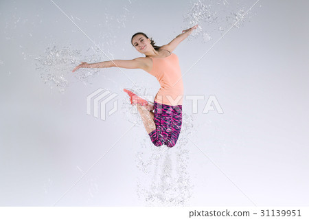 Woman jumping in the studio and splashing water Woman jumping in the studio and splashing water 31139951