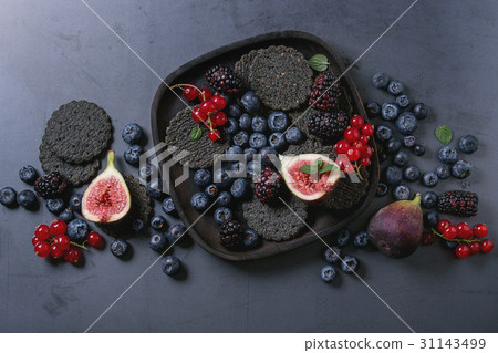 Variety of berries and figs with black crackers Variety of berries and figs with black crackers 31143499