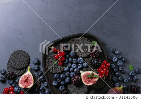 Variety of berries and figs with black crackers Variety of berries and figs with black crackers 31143500