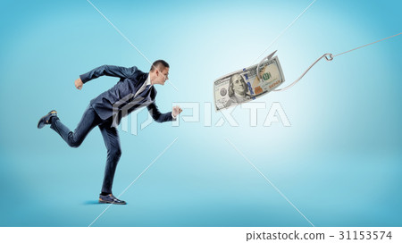 A businessman running after a dollar bill that's A businessman running after a dollar bill that's 31153574