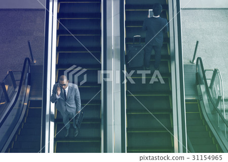 Business people using escalator and talking phone Business people using escalator and talking phone 31154965
