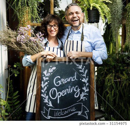 Adult Man and Woman Standing with Grand Opening Sign Adult Man and Woman Standing with Grand Opening Sign 31154975