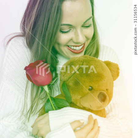 A woman is holding rose and bear doll. 31156534