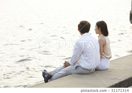 a couple is sitting on the river bank. a couple is sitting on the river bank. 31171314