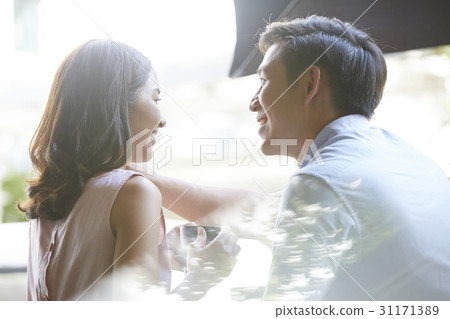 a man is touching his girlfriend hair with smiles on their faces. 31171389