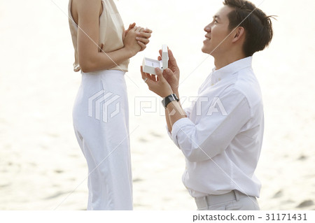 Man is kneeling and giving an proposal ring to his girlfriend. 31171431