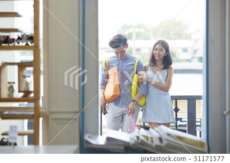 A happy couple is standing in front of the window of a store. A happy couple is standing in front of the window of a store. 31171577