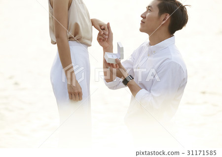 Man is kneeling, hold his girlfriend's hand and proposing to her. 31171585