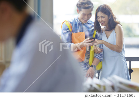 Young couple is smiling when reading looking at the mobilephone Young couple is smiling when reading looking at the mobilephone 31171603