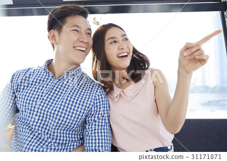 A happy couple is sitting on a cable car and looking at outside. A happy couple is sitting on a cable car and looking at outside. 31171871