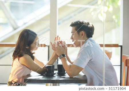 A couple is playing happily with their hands in the coffee shop. A couple is playing happily with their hands in the coffee shop. 31171904