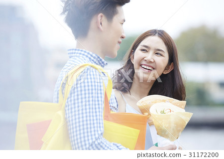 a couple is holding food, smiling and talking happily a couple is holding food, smiling and talking happily 31172200