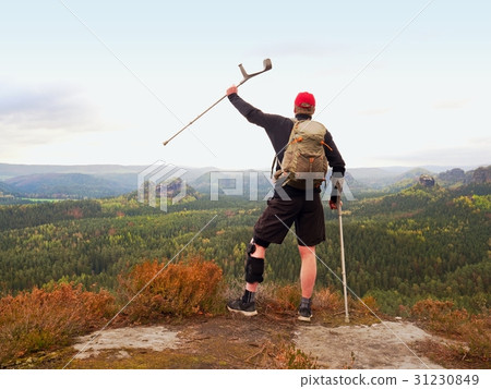 Wounded tourist with crutch above head achieved 31230849