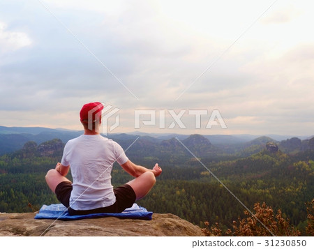 Alone sit man practicing Yoga pose on rocky peak 31230850