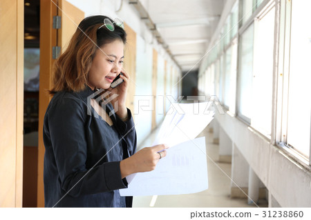woman is holding documents with right hand and mobile phone on l woman is holding documents with right hand and mobile phone on l 31238860